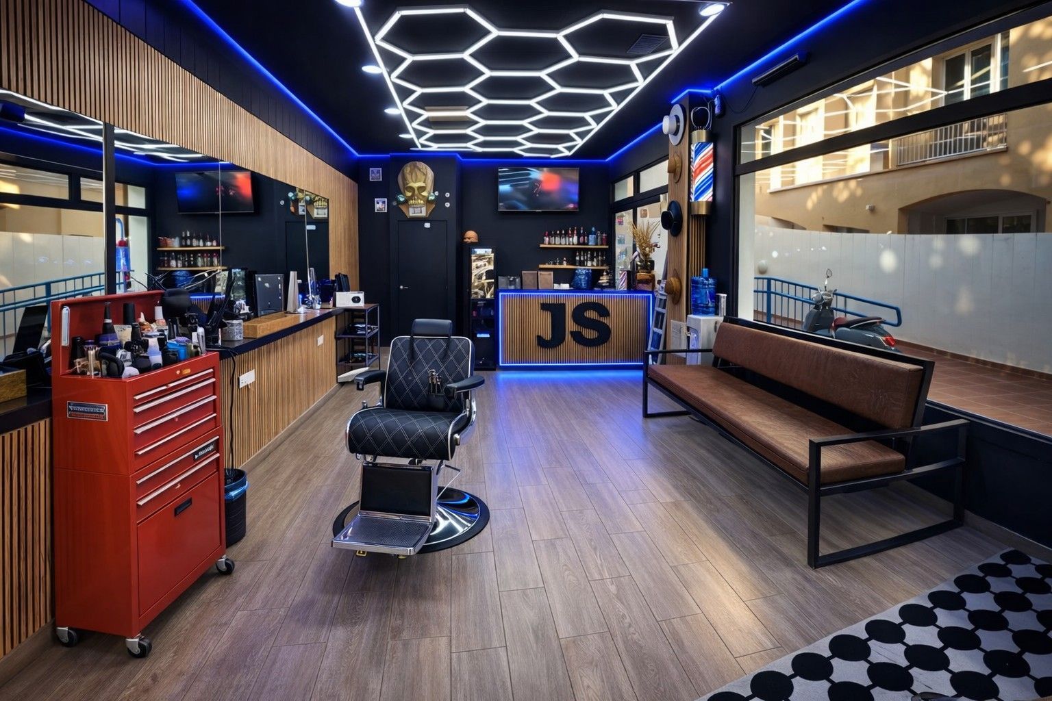 Interior real de Jhon Suarez Barber Shop en Rota: sillón de barbero clásico, luces hexagonales y mostrador JS iluminado en azul